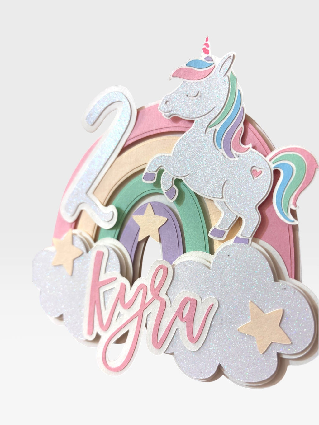 Paper Party Studio personalized unicorn cake topper with pastel rainbow, clouds, and custom name and age.