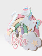 Paper Party Studio personalized unicorn cake topper with pastel rainbow, clouds, and custom name and age.