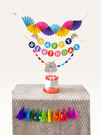 Paper Party Studio unicorn rainbow birthday party decoration set with personalised cake topper on a cake table