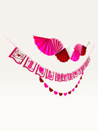 Paper Party Studio Valentine's decoration set with I Love You banner, paper fan backdrop, and scallop garland.