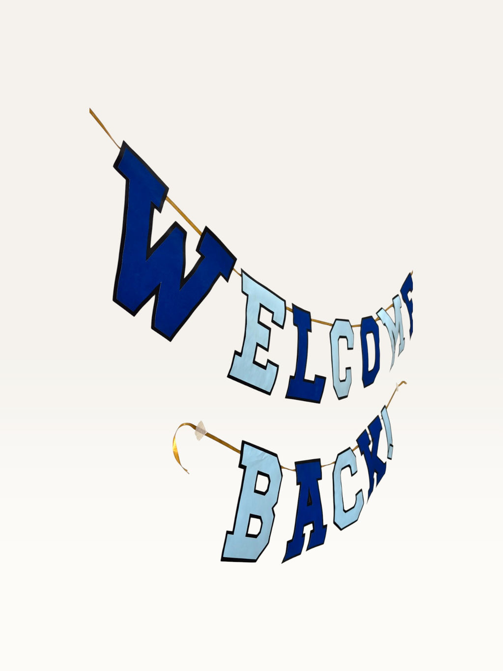 Paper Party Studio Welcome Back banner featuring navy and sky blue varsity letters on a gold cord for homecomings.