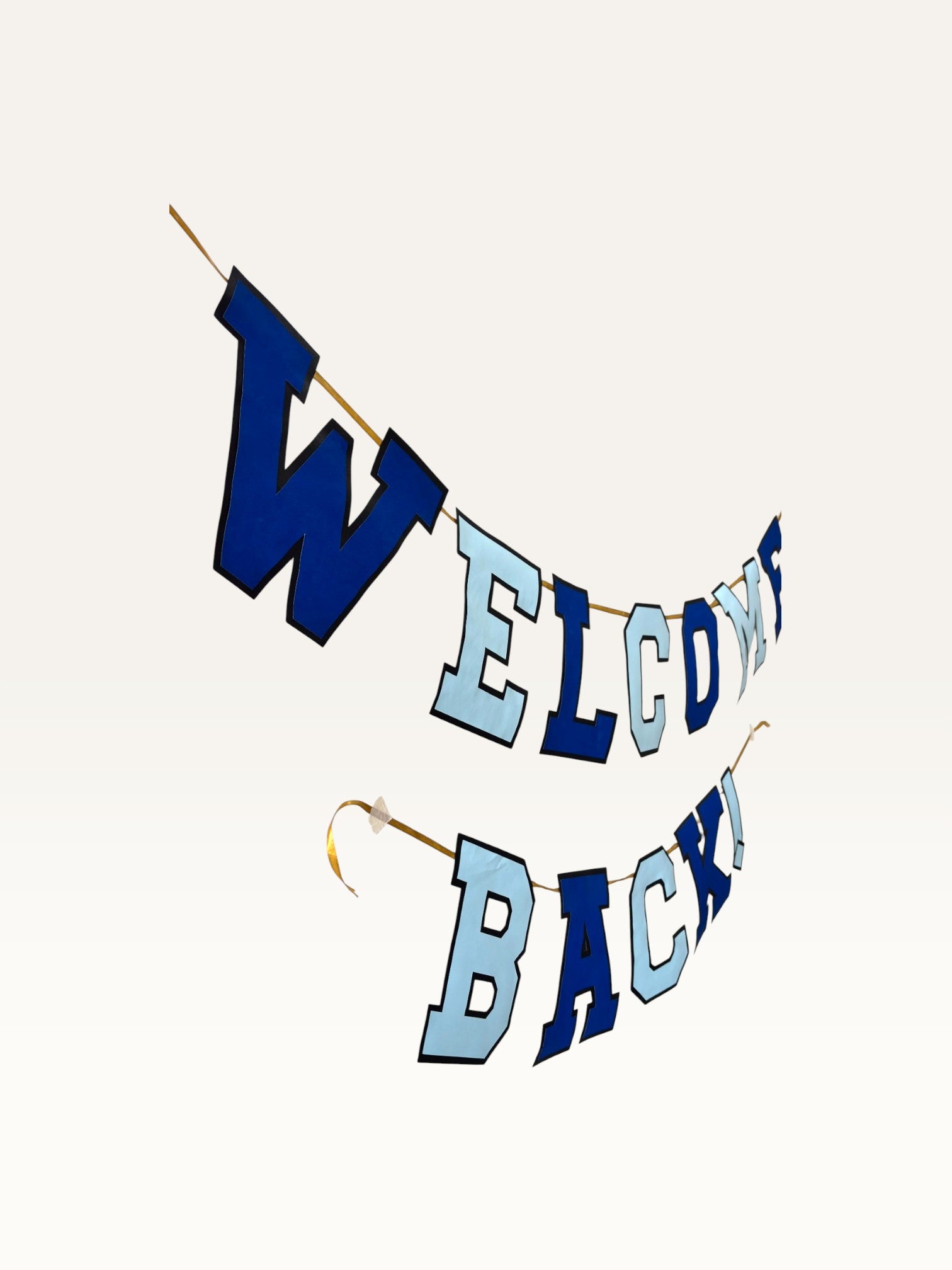 Paper Party Studio Welcome Back banner featuring navy and sky blue varsity letters on a gold cord for homecomings.