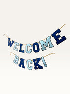 Paper Party Studio Welcome Back banner in navy and sky blue varsity letters strung on a gold cord for homecomings.