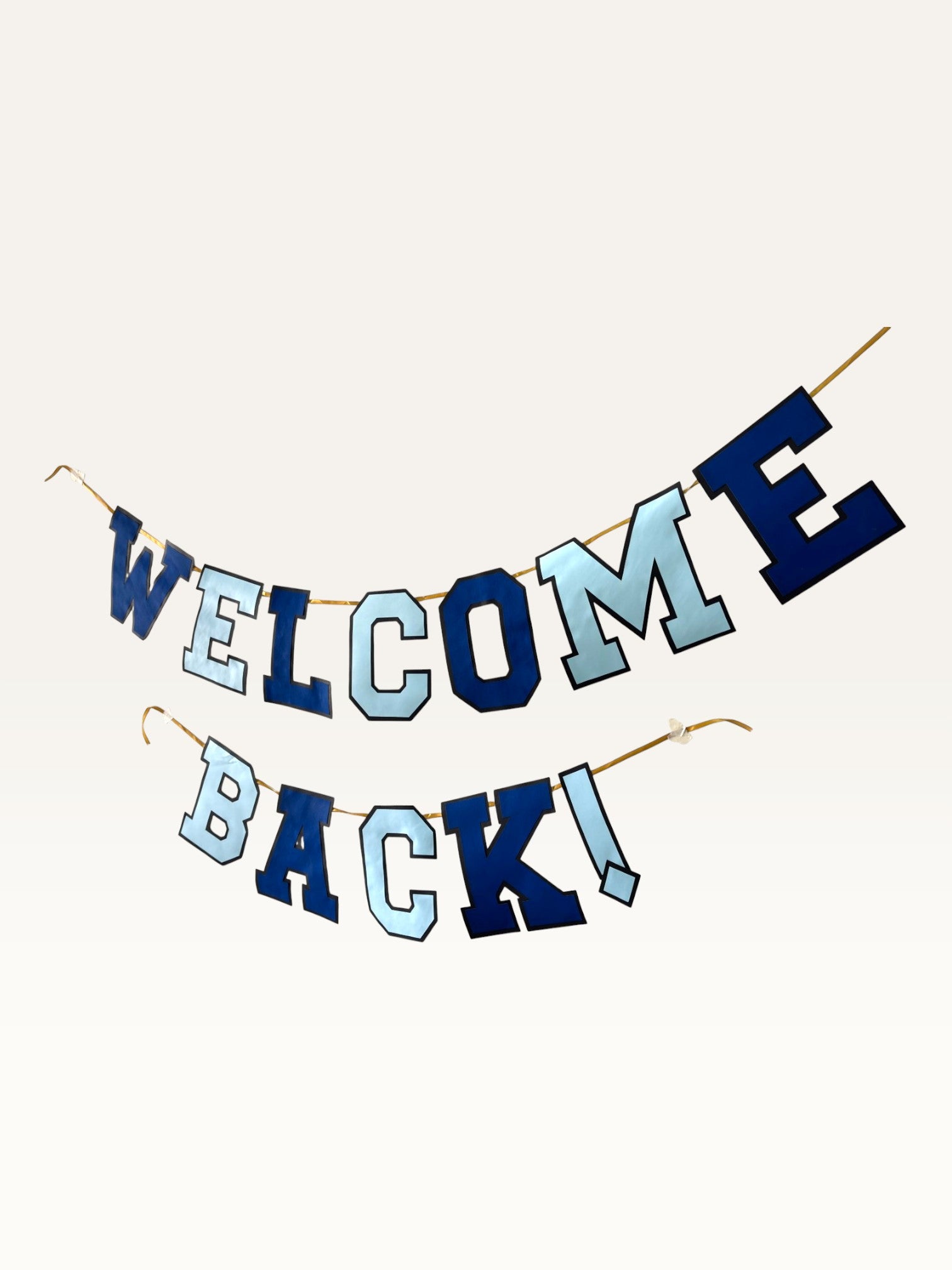 Paper Party Studio Welcome Back banner in navy and sky blue varsity letters strung on a gold cord for homecomings.