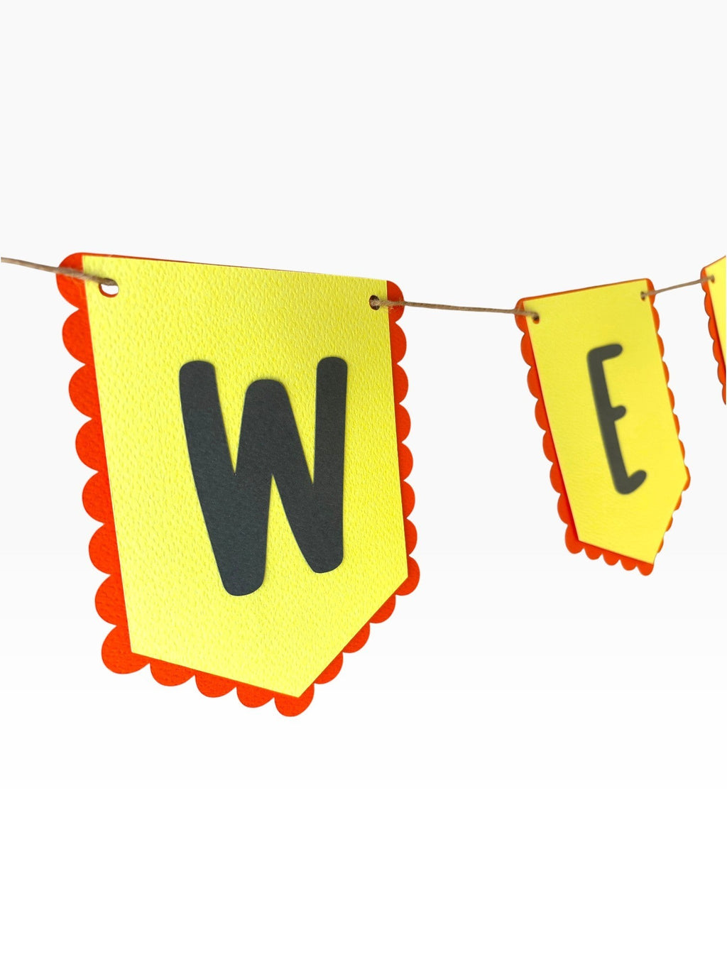 Paper Party Studio yellow paper bunting with scalloped red edges and black 'W' and 'E' letters.