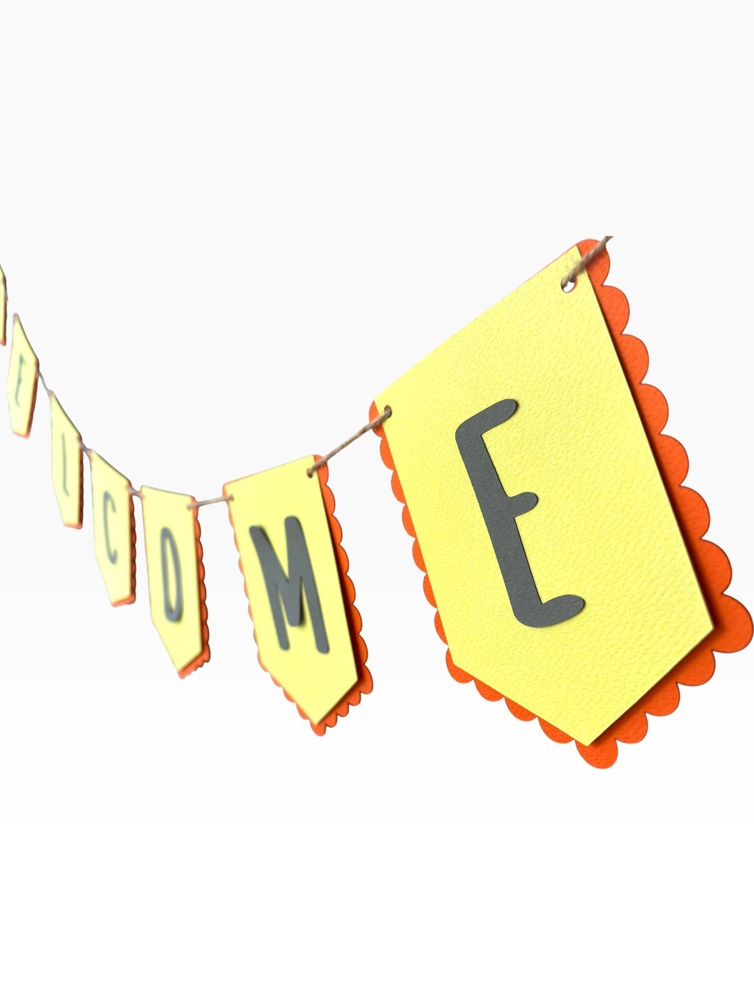 Paper Party Studio yellow paper bunting with scalloped red edges and black letters spelling 'WELCOME'.