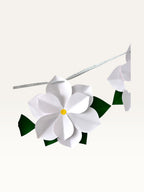 Paper Party Studio white 3D paper flower garland with yellow centers and green leaves on a silver hanging cord